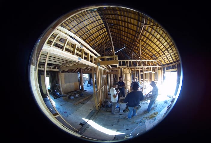 The crew — Sasha, Aditya, and the workers — having breakfast on site inside the framed extension, shot on a fisheye lens.